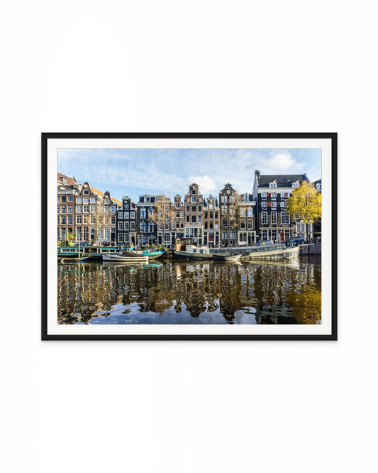 Casas tradicionales de Ámsterdam frente al canal con barcos amarrados y reflejos en el agua