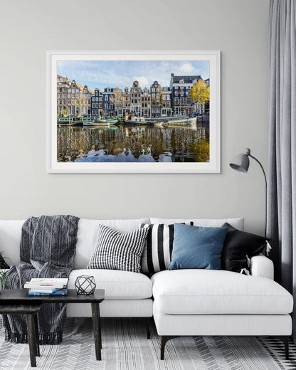 Casas tradicionales de Ámsterdam frente al canal con barcos amarrados y reflejos en el agua