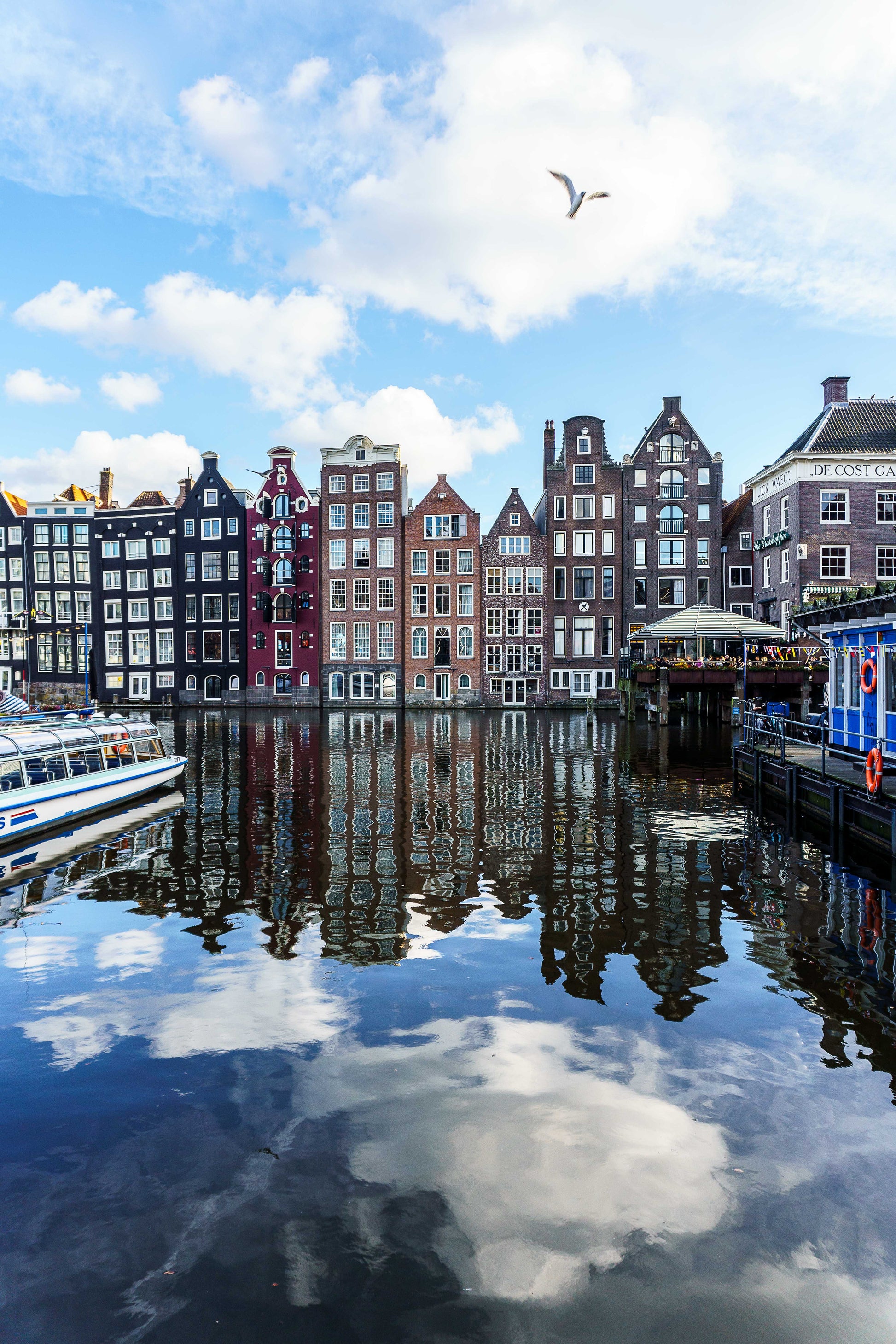 Casas tradicionales de Ámsterdam reflejadas en el agua del canal en un día luminoso