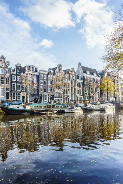 Canal de Ámsterdam en otoño con casas tradicionales, barcas y reflejos sobre el agua.